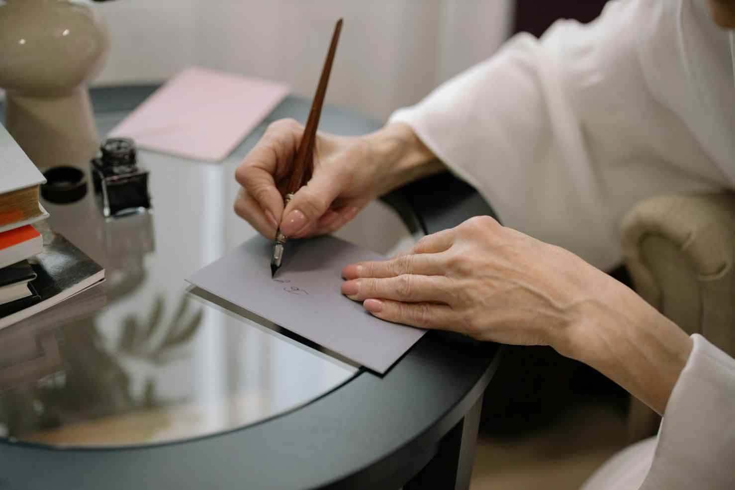 Woman writes a letter using a calligraphy pen to showcase a formal letter of recommendation that students need for their college application process.